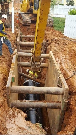 worker laing a water pipe underground